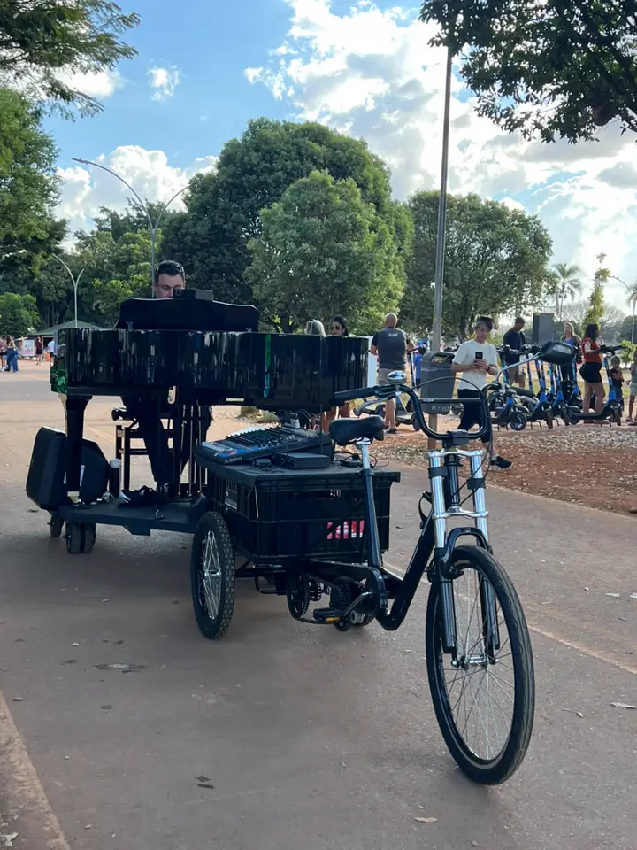 Triciclo preto do Piano Bike acoplado à carreta do piano no Parque da Cidade